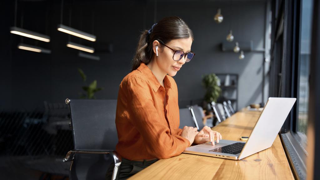 young adult working at desk in office with laptop